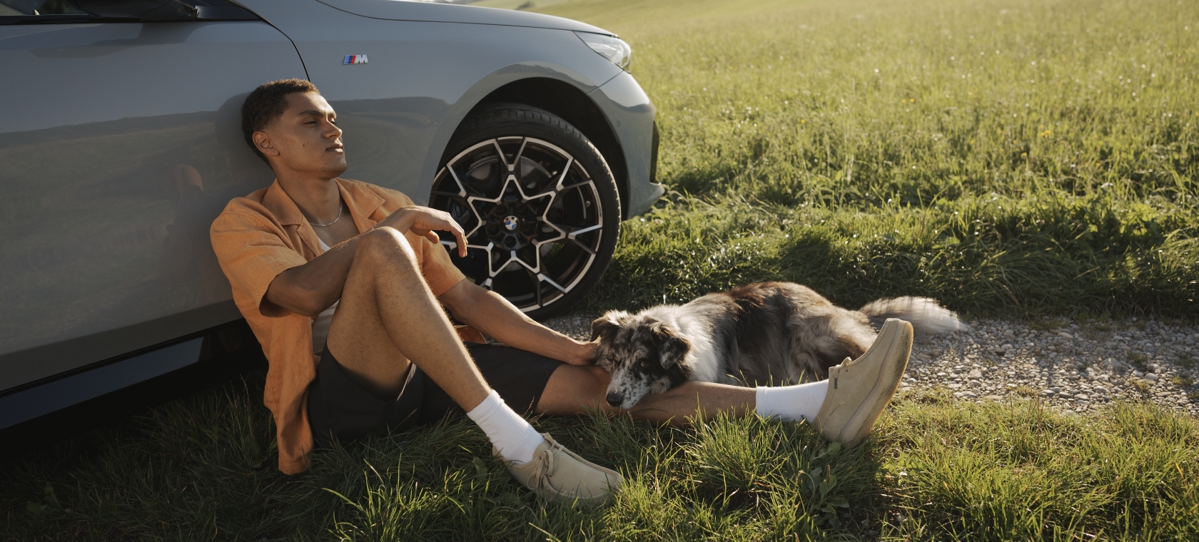 Man sitting against BMW with dog